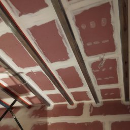 Jarek Śmigiel - Montaż sufitu podwieszanego: konstrukcja z profili metalowych i płyt gipsowo-kartonowych, wstępnie zaszpachlowane łączenia, widoczne przewody.