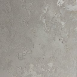 Jarek Śmigiel - Szara ściana z dekoracyjną, nierównomierną fakturą przypominającą kamień lub beton, z widocznymi jaśniejszymi plamami i delikatnymi nierównościami.