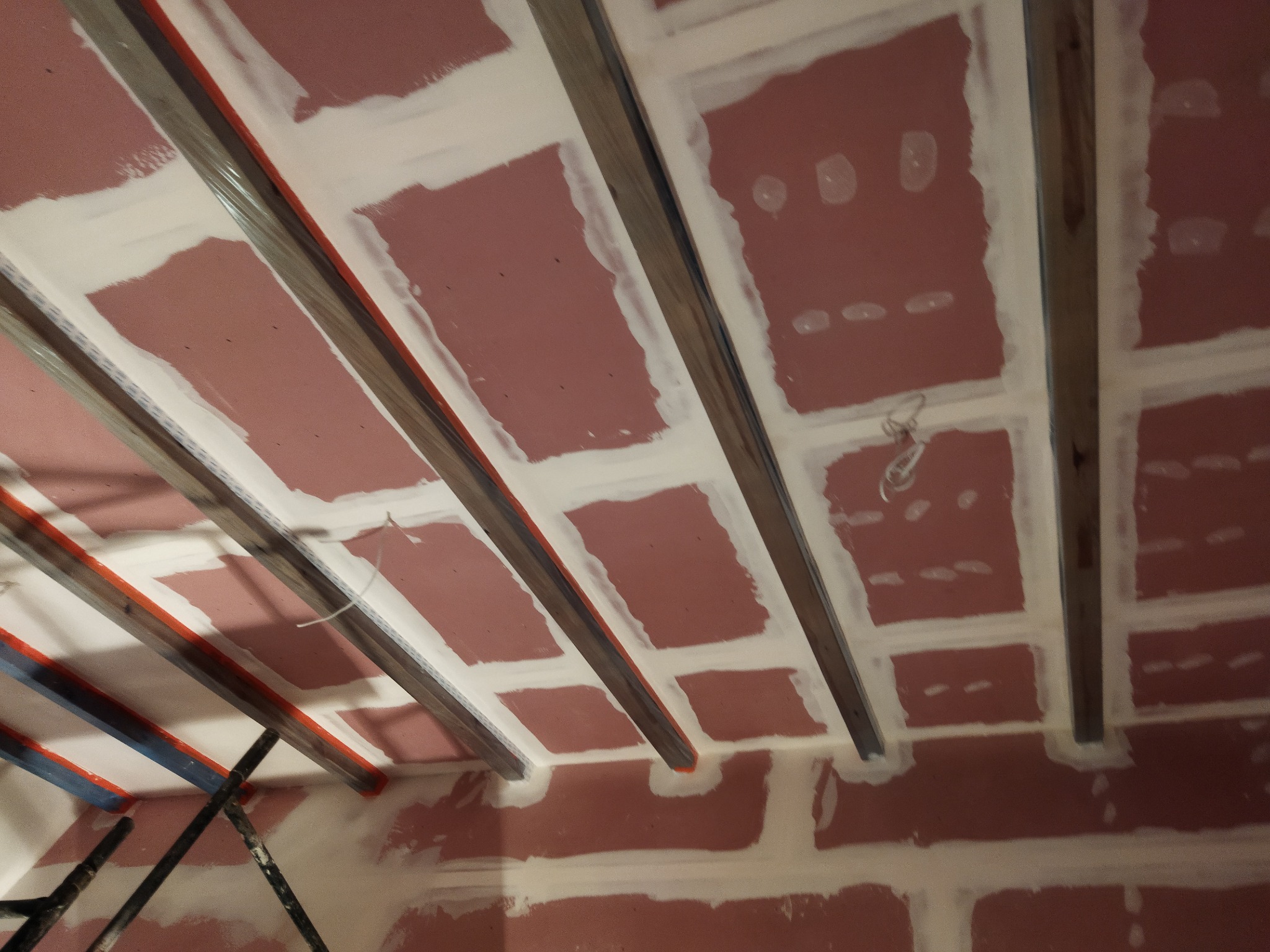 Montaż sufitu podwieszanego: konstrukcja z profili metalowych i płyt gipsowo-kartonowych, wstępnie zaszpachlowane łączenia, widoczne przewody.