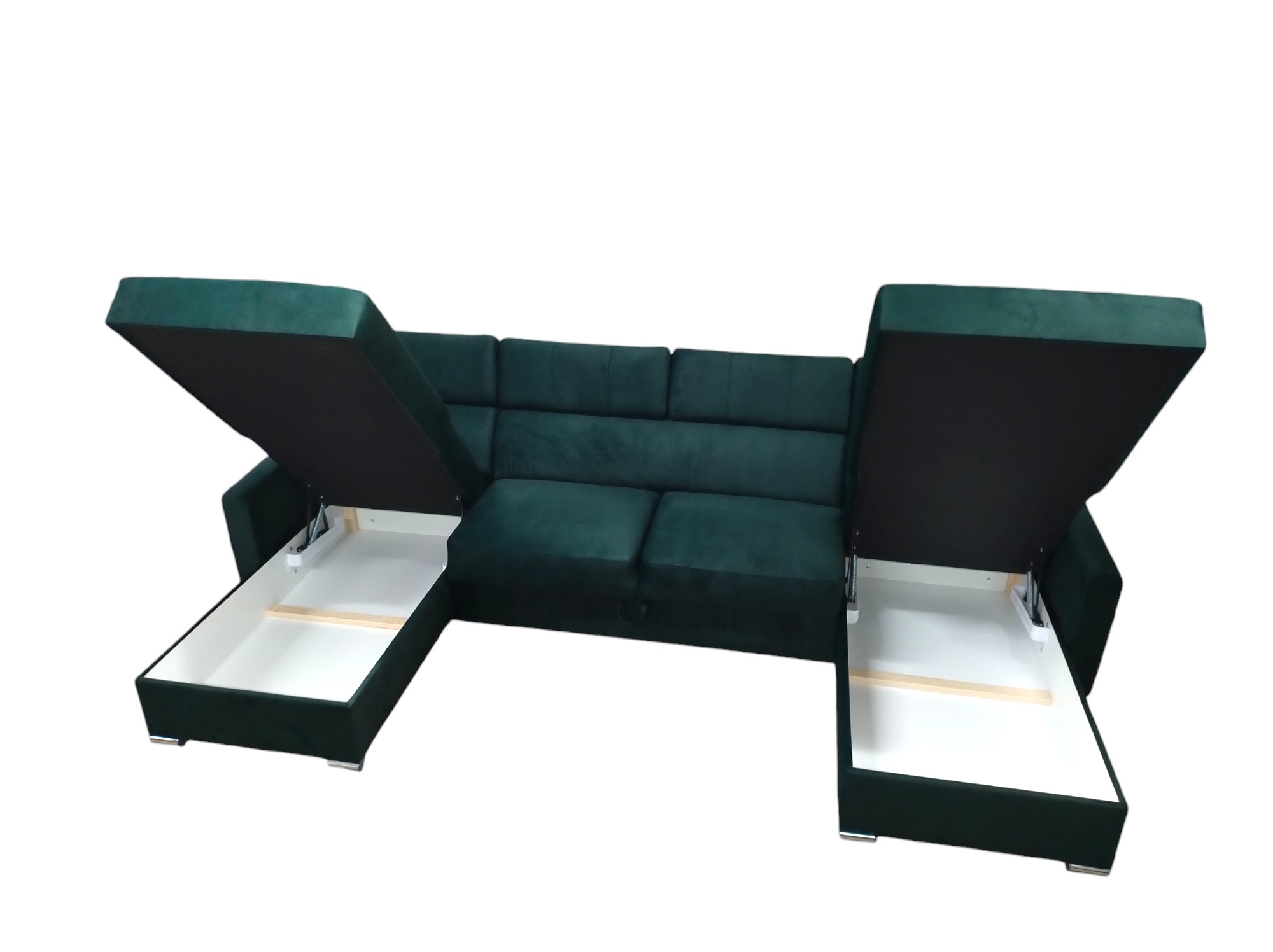 Rozłożona, ciemnozielona kanapa narożna z welurową tapicerką, ukazująca białe, wysuwane pojemniki na pościel po obu stronach.
