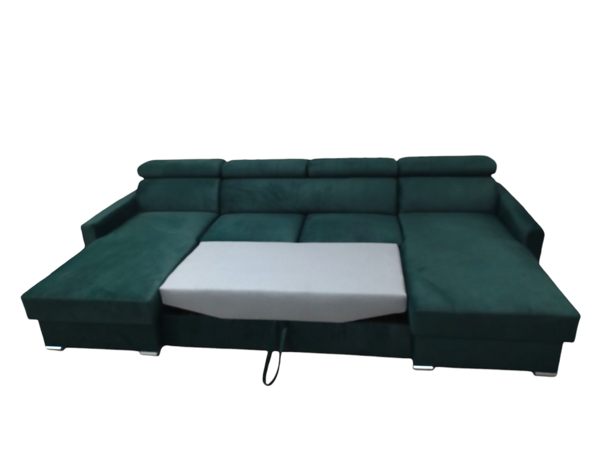 Rozłożona, ciemnozielona kanapa narożna z funkcją spania, widoczny wysuwany element w kolorze szarym, na niskich, chromowanych nóżkach.