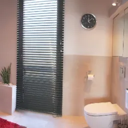 Nowoczesna łazienka na poddaszu z wanną, umywalką, toaletą, lustrem w szafce, roletami okiennymi i fototapetą z motywem morza.