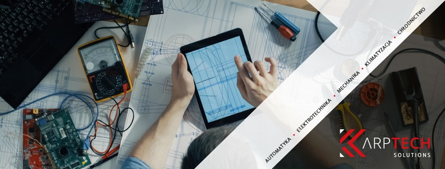 Pracownik przegląda schemat elektryczny na tablecie, obok leżą narzędzia, miernik i płyty elektroniczne.