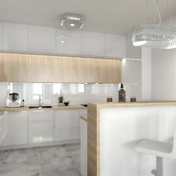 Amable - Nowoczesna kuchnia z białymi szafkami, drewnianymi akcentami i barem. Kryształowy żyrandol i kwiaty dodają elegancji. Widoczny fragment ściany z motywem roślinnym.