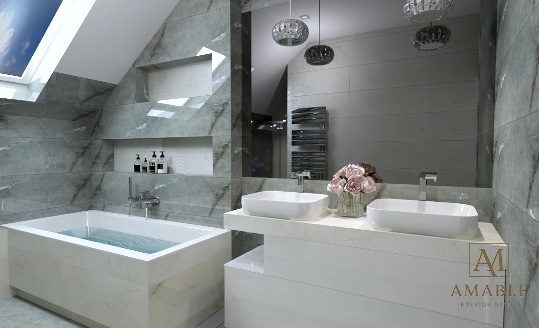 Elegancka łazienka na poddaszu z marmurowymi płytkami, wanną z wodą, podwójną umywalką i wiszącymi lampami. Widoczny fragment okna dachowego i logo projektanta.