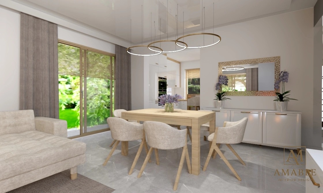 Jasna jadalnia z drewnianym stołem, krzesłami w odcieniach beżu i nowoczesnym oświetleniem. W tle widok na ogród przez okno z żaluzjami.