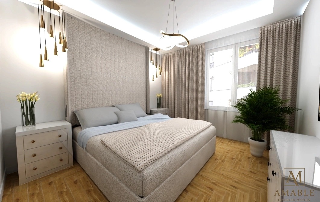 Jasna sypialnia z łóżkiem, drewnianą podłogą i rośliną w doniczce przy oknie. Nad łóżkiem wiszą nowoczesne lampy. Na szafce nocnej wazon z kwiatami.