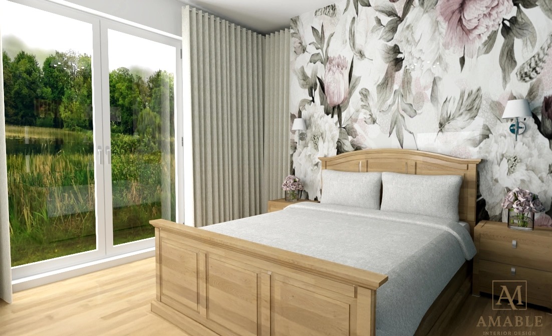 Jasna sypialnia z drewnianym łóżkiem na tle ściany w kwiaty. Duże okno z widokiem na zieleń. Neutralne barwy i delikatne oświetlenie tworzą spokojny, relaksujący klimat.