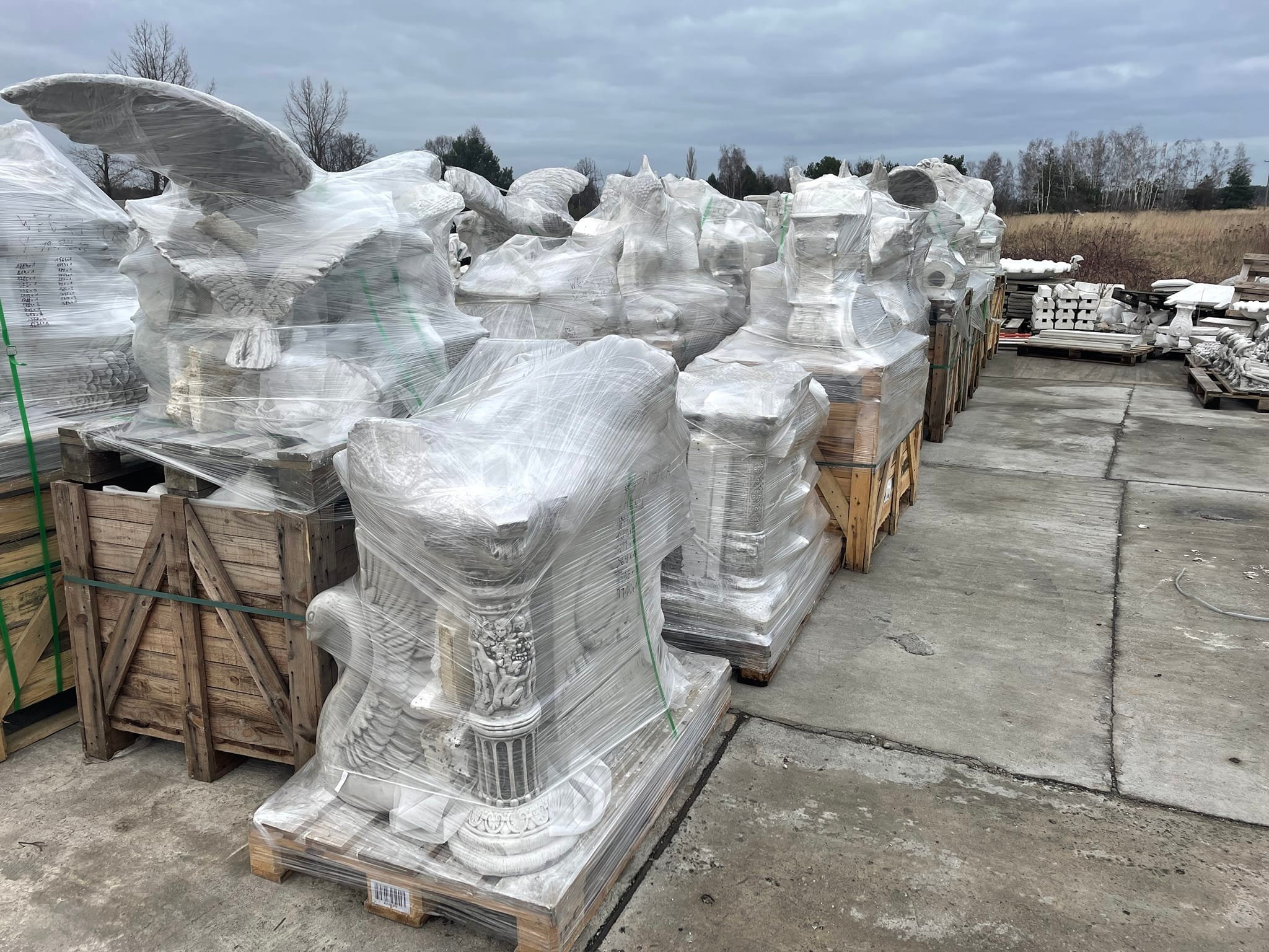 Figury ogrodowe (orzeł, wazon) z betonu architektonicznego zapakowane w folię na paletach, przygotowane do transportu.