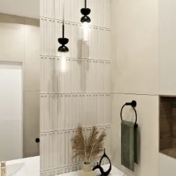 Nowoczesna łazienka z beżowymi płytkami o pionowym wzorze, wiszącymi lampami w stylu retro, białym blatem z umywalką i złotą baterią oraz dekoracyjnym wazonem z suszonymi trawami, uzupełniona...
