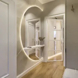 Nowoczesny przedpokój z okrągłym lustrem podświetlanym LED, drewnianą podłogą i minimalistycznymi wieszakami ściennymi.