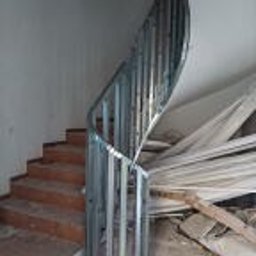 Wykończmy To - Konstrukcja schodów spiralnych wykonana z metalowych profili, przygotowana do obłożenia płytami, widoczne stopnie schodów i elementy składowane w tle.