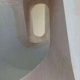 Wykończmy To - Surowe ściany z gładzią w Wojcieszkowie, widok z dołu na owalne okno w suficie, widoczne niedoskonałości i ślady po szpachlowaniu.