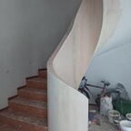 Wykończmy To - Surowe drewniane schody z falistą ścianką działową z płyty, widoczne ślady prac wykończeniowych, rower oparty o ścianę w tle.