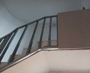 Konstrukcja schodów z profili metalowych przygotowana do obłożenia płytami. Widoczna płyta gipsowo-kartonowa oparta o ścianę. Surowe wykończenie, widoczne elementy mocujące.