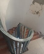 Konstrukcja metalowa schodów z profili, przygotowana pod obłożenie płytami, widoczne niedoskonałości ściany w tle.