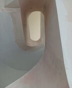 Surowe ściany z gładzią w Wojcieszkowie, widok z dołu na owalne okno w suficie, widoczne niedoskonałości i ślady po szpachlowaniu.