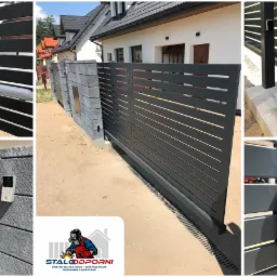 Nowoczesna, pozioma brama przesuwna w kolorze antracytowym z automatyką i domofonem na słupku z szarej kostki, na tle domu jednorodzinnego.