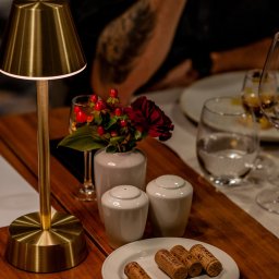 kierophoto - Ustawienie stołu z lampką, korkami po winie na talerzu, kwiatami w wazonie i przyprawnikami. Ciepłe światło, elegancka aranżacja.