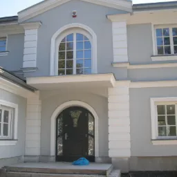 Elewacja domu z zainstalowanym systemem alarmowym, widoczny czujnik nad oknem na pierwszym piętrze.