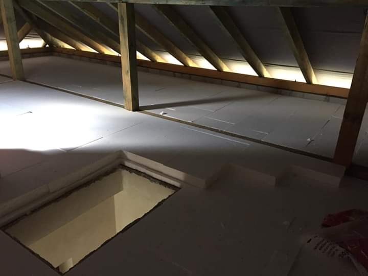 Poddasze z drewnianą konstrukcją dachu i izolacją termiczną podłogi w postaci białych płyt styropianowych, widoczny otwór w podłodze.