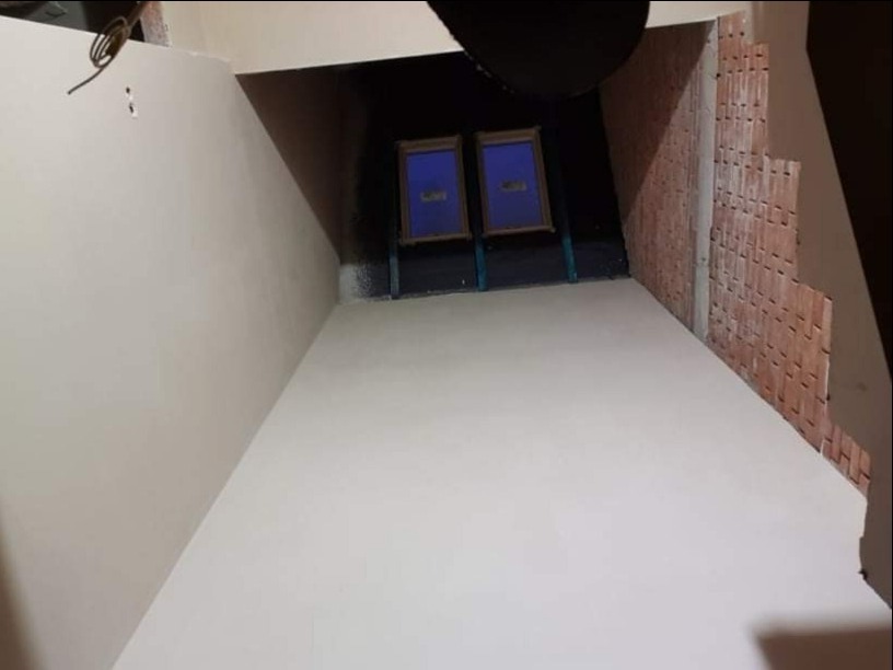 Wnętrze po nałożeniu gładzi, widoczny fragment ściany z cegły, dwa obrazy w tle i instalacja elektryczna pod sufitem.