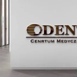Metalowe litery z nazwą 'ODENT' i napisem 'CENTRUM MEDYCZNE' na białej ścianie w nowoczesnym wnętrzu, widok z boku.