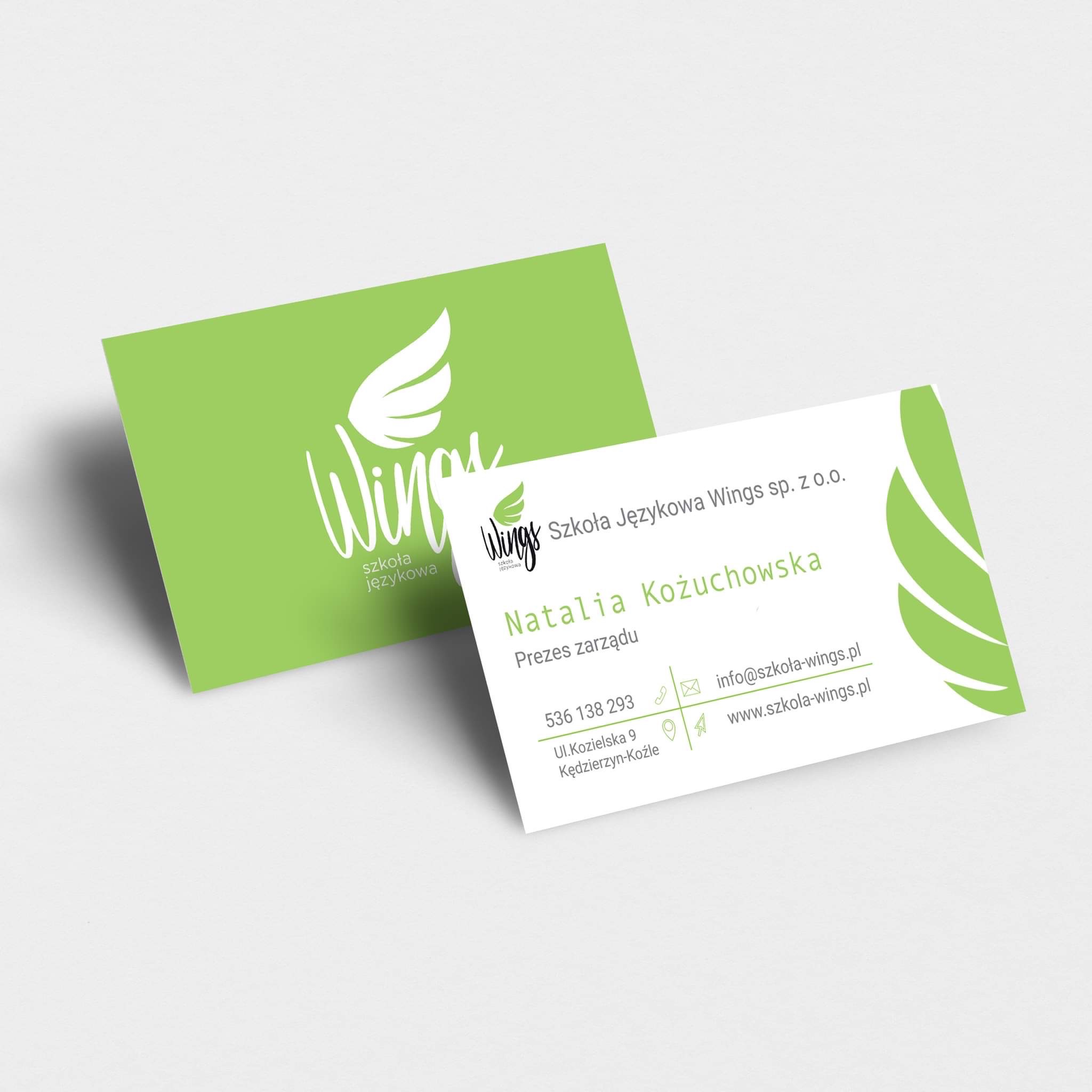 Dwie wizytówki szkoły językowej Wings, jedna zielona z logo skrzydła, druga biała z danymi kontaktowymi Natalii Kożuchowskiej, Prezesa Zarządu.