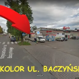 Zdjęcie z poziomu ulicy przedstawia budynek sklepu spożywczego z parkingiem, widoczny znak drogowy ograniczenia prędkości do 10 km/h.