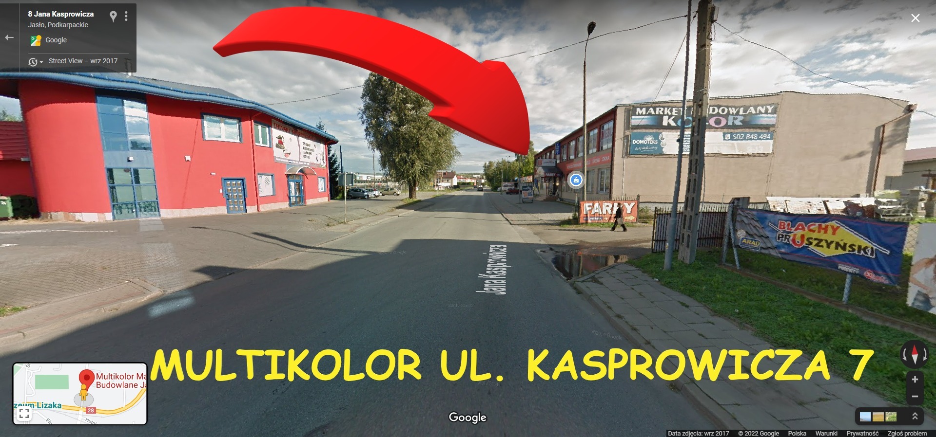 Ulica Jana Kasprowicza w Jaśle z widokiem na budynki handlowe, w tym jeden oznaczony jako 'Market Budowlany Kolor' i baner reklamowy 'Blachy Pruszyński'.