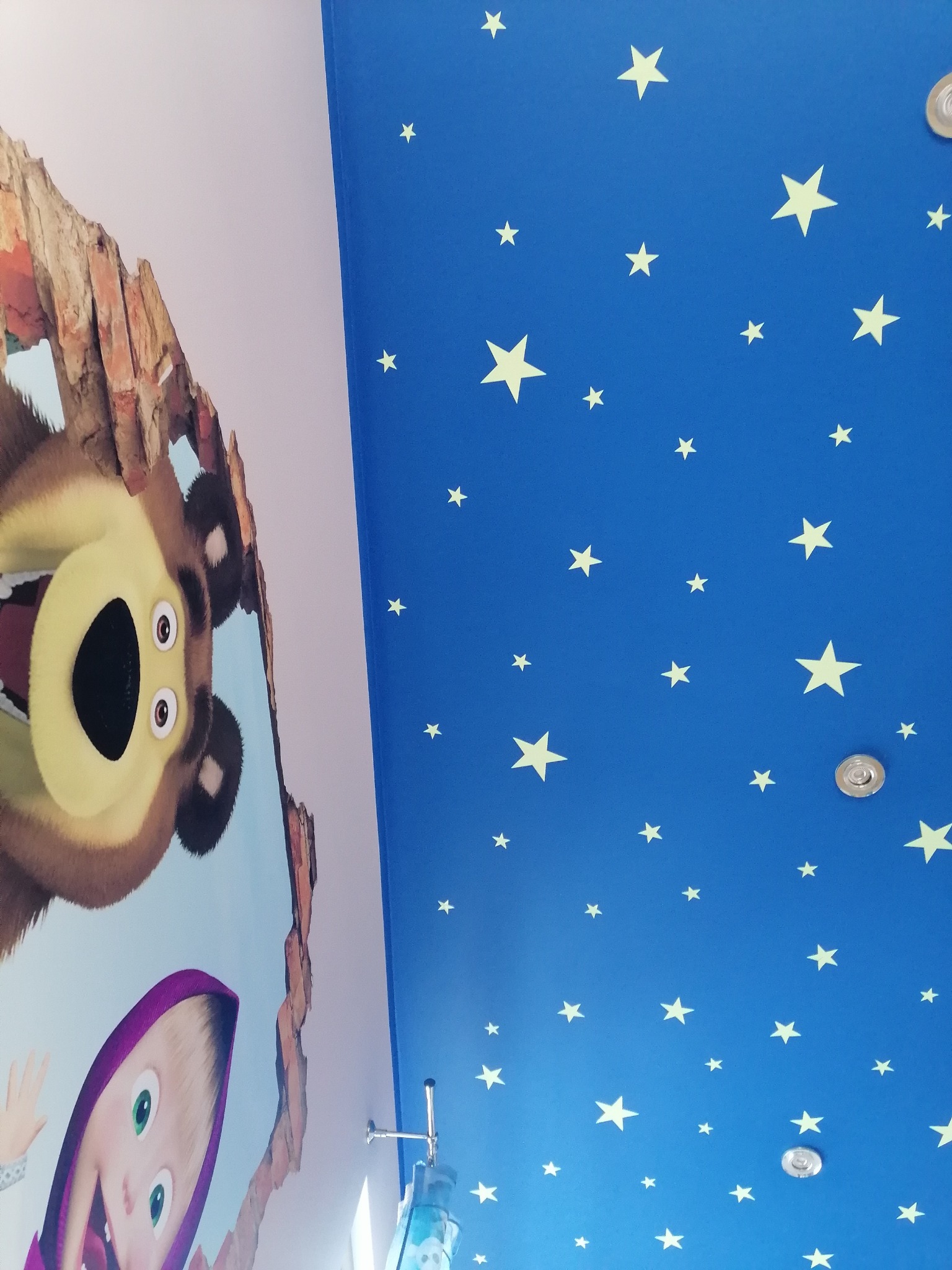 Niebieski sufit w gwiazdki z wizerunkiem postaci z bajki Masha i Niedźwiedź, widoczne oświetlenie punktowe.