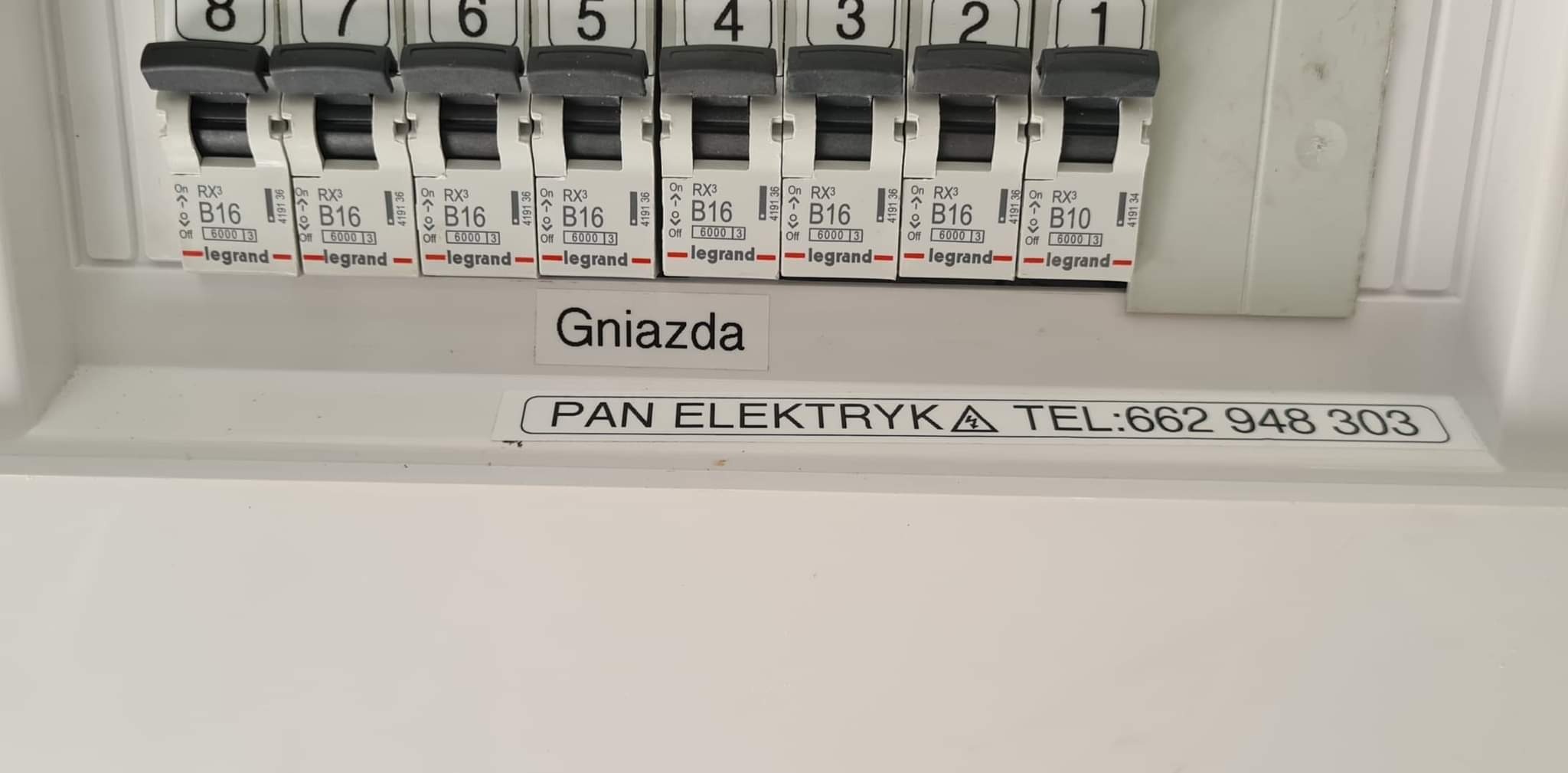 Tablica rozdzielcza z bezpiecznikami B16 i B10 marki Legrand, podpisana 'Gniazda' z naklejką 'PAN ELEKTRYKA TEL:662 948 303'.