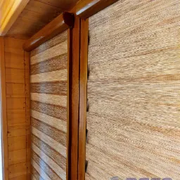 Zamknięte drewniane rolety dzień noc w rustykalnym wnętrzu z boazerią, widoczny mechanizm i łańcuszek sterujący.