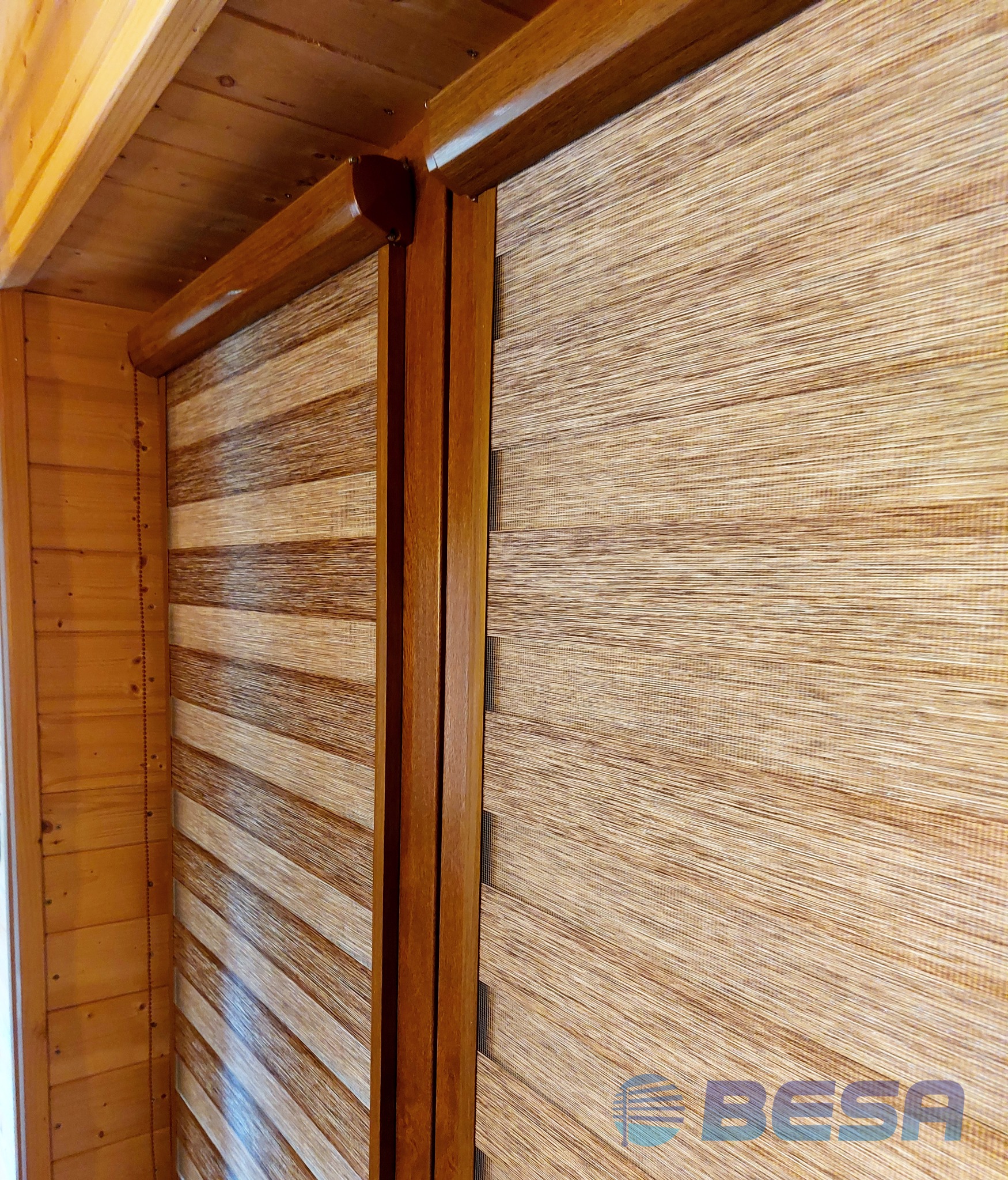 Zamknięte drewniane rolety dzień noc w rustykalnym wnętrzu z boazerią, widoczny mechanizm i łańcuszek sterujący.