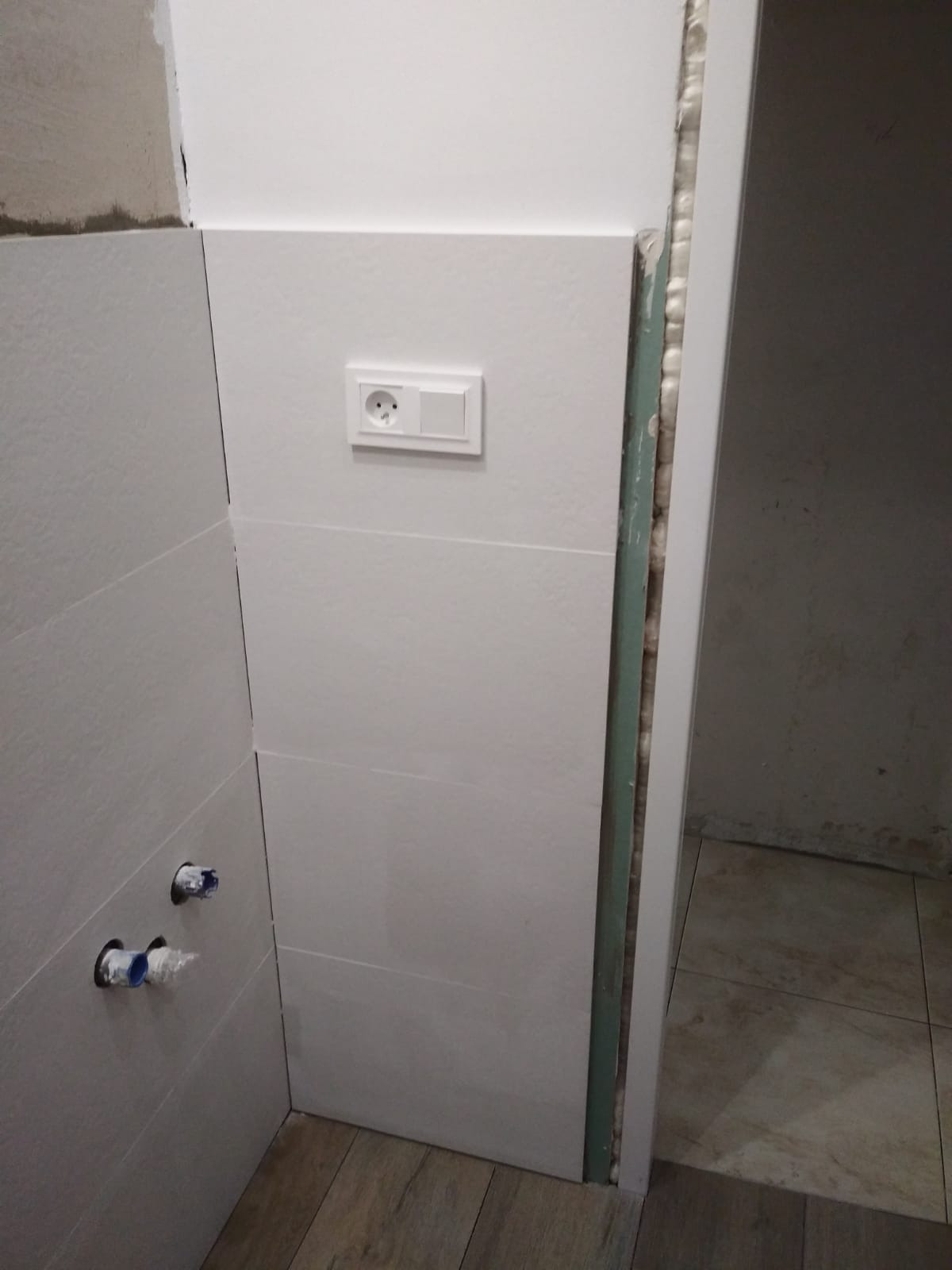 Montaż płyty karton gips w łazience z widocznymi rurami i gniazdkiem elektrycznym, przed wykończeniem fug.