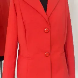 Czerwona damska marynarka z błyszczącymi guzikami na czarnym manekinie, odbicie w lustrze z lewej strony.