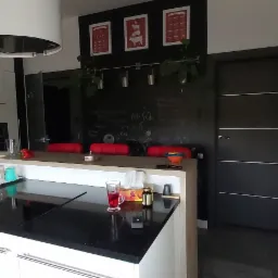 Nowoczesna kuchnia w Zabrzu z czarnym blatem, białymi szafkami i ścianą z tablicą kredową, na kt&oacute;rej widnieją wzory matematyczne i wiszą dekoracje.