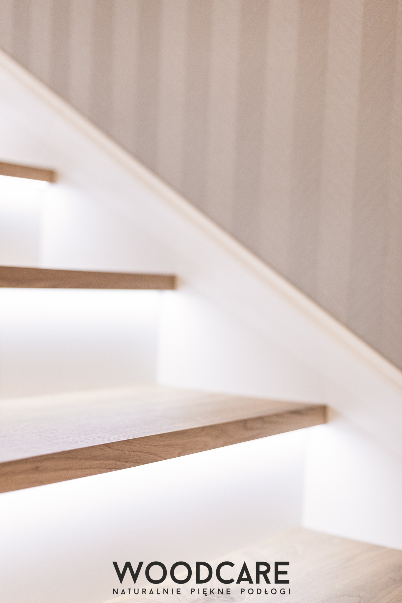 Minimalistyczne schody z podświetleniem LED, drewniane stopnie o ciepłym odcieniu, białe boki. Ujęcie z dołu, widoczny fragment ściany w tle.