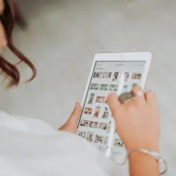 Kobieta przegląda portfolio projektów wnętrz na tablecie, używając rysika; widoczne zdjęcia aranżacji mieszkań i biur.