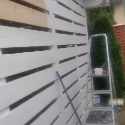 Malowanie drewnianej podsufitki na biało w Ożarowie Mazowieckim, widoczna drabina, pędzel i częściowo pomalowane deski.