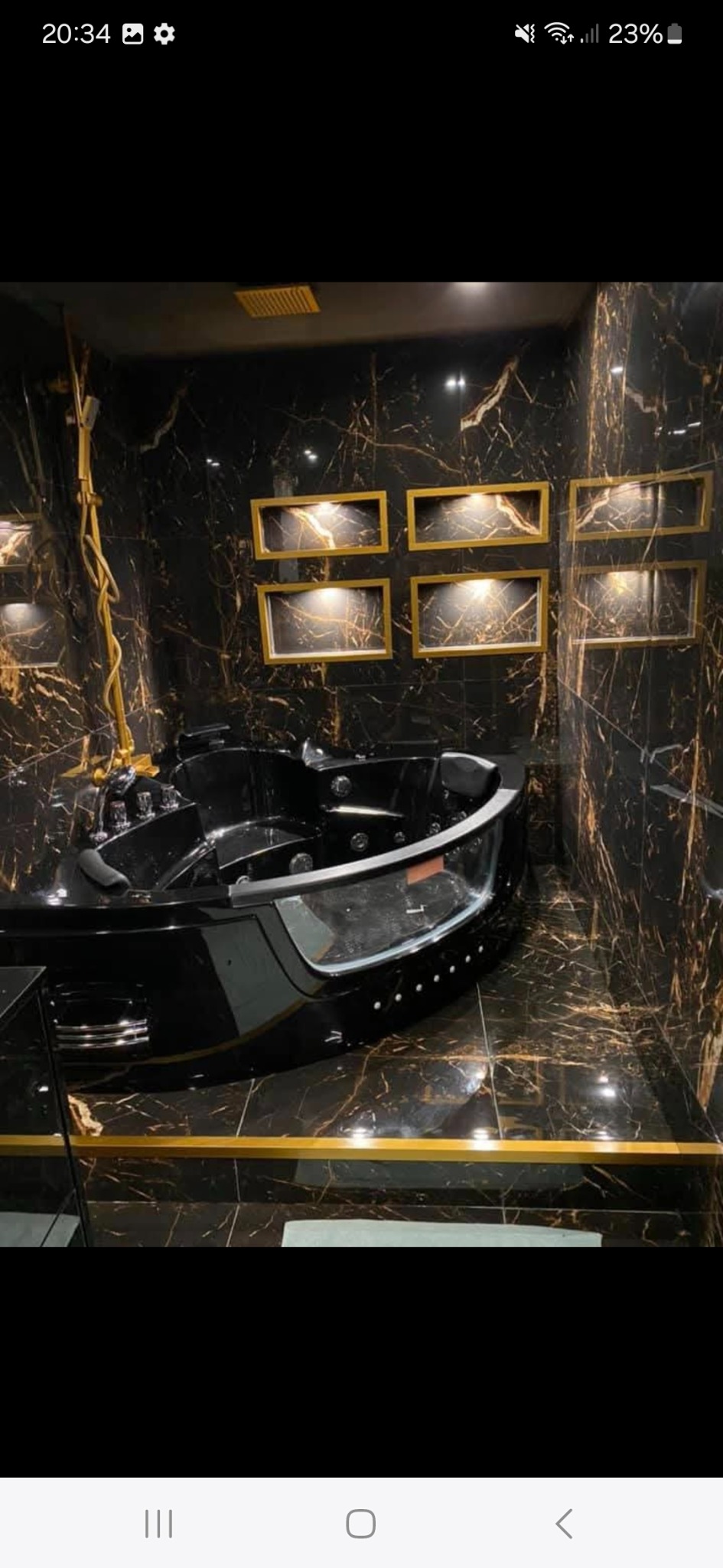 Luksusowa łazienka z czarną wanną jacuzzi, złotymi akcentami i marmurowymi płytkami. Oświetlenie punktowe podkreśla elegancję wnętrza.