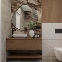 Nowoczesna łazienka z umywalką nablatową, czarną armaturą, owalnym lustrem w czarnej ramie, drewnianą szafką pod umywalką i wiszącą toaletą.