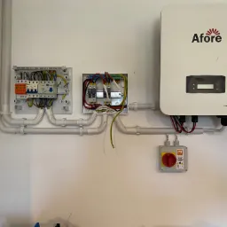 Rozdzielnice elektryczne i falownik Afore zamontowane na ścianie w Trzcińsku-Zdroju, widoczne kable i peszle.