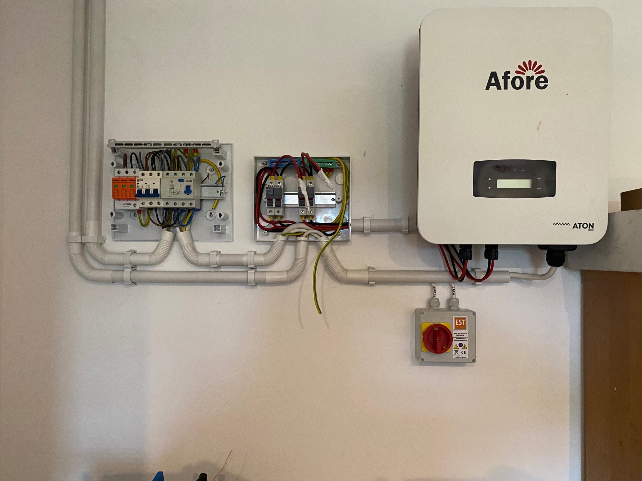 Rozdzielnice elektryczne i falownik Afore zamontowane na ścianie w Trzcińsku-Zdroju, widoczne kable i peszle.