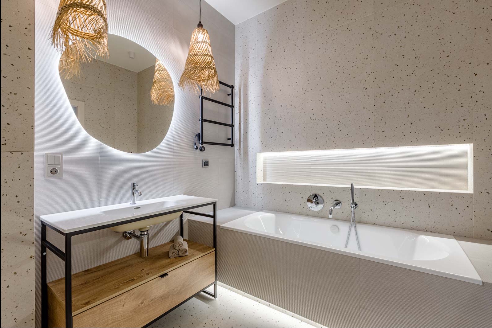 Nowoczesna łazienka w Ząbkach z owalnym lustrem podświetlanym LED, wiszącymi lampami z naturalnego materiału i wanną z podświetleniem. Minimalistyczny design.