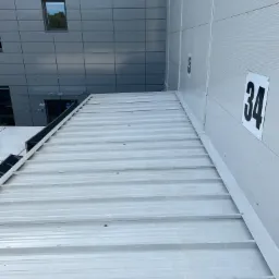 Biała elewacja budynku przemysłowego z numerami 34 i 35, widok z dołu na górę.