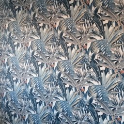 VPBud - Ściana pokryta tapetą z motywem tropikalnych liści w odcieniach szarości, błękitu i bieli, z delikatnymi akcentami pomarańczowych kwiatów.