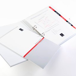 ANS Group Spółka z ograniczona odpowidzialnością - Otwarty, biały segregator z widoczną zawartością: kalendarz, dokumenty firmowe z logo 'CASH', czerwone akcenty graficzne. Widok z góry, ostre światło.