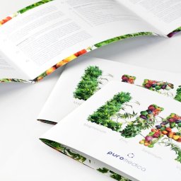 ANS Group Spółka z ograniczona odpowidzialnością - Rozłożone, trójdzielne broszury Puromedica z grafiką roślinną i warzywną, prezentujące informacje o minerałach i witaminach na białym tle. Widoczne detale druku.