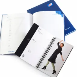 Otwarty kalendarz książkowy na spirali z datą 30 maja i zdjęciem kobiety, obok drugi otwarty kalendarz z datą 16 października, na tle granatowy kalendarz Pepco.